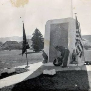Black and white photograph of a Mr. James R. Coyle placing a wreath beneath the 1943 built Servicemembers Monument in East Helena's Main Street Park.