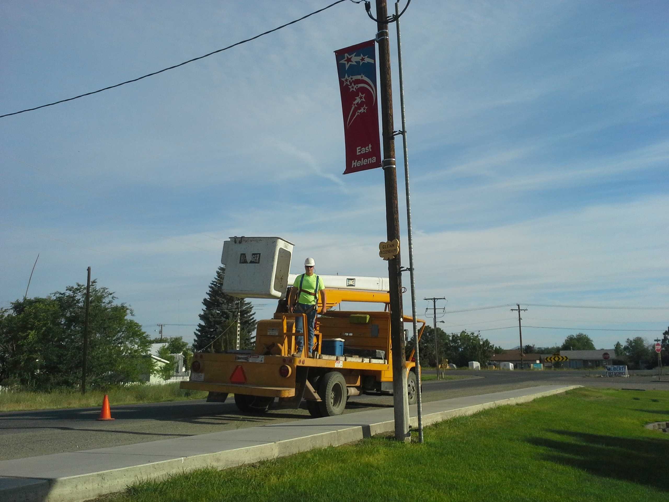 East Helena Public Works lift truck with employee getting ready to change a street banner.